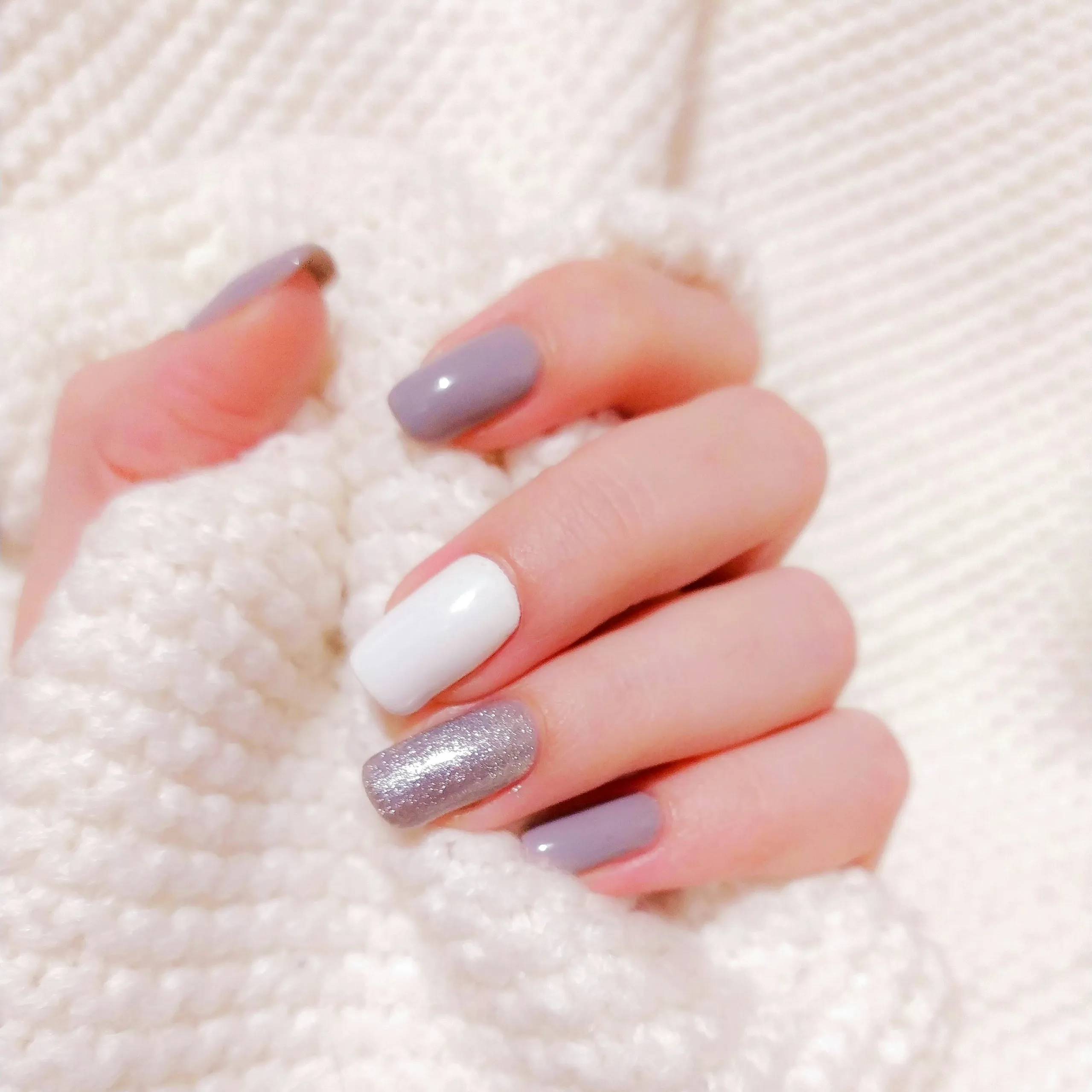 Manicure hybrydowy: szaro-białe paznokcie ze srebrnym brokatowym akcentem