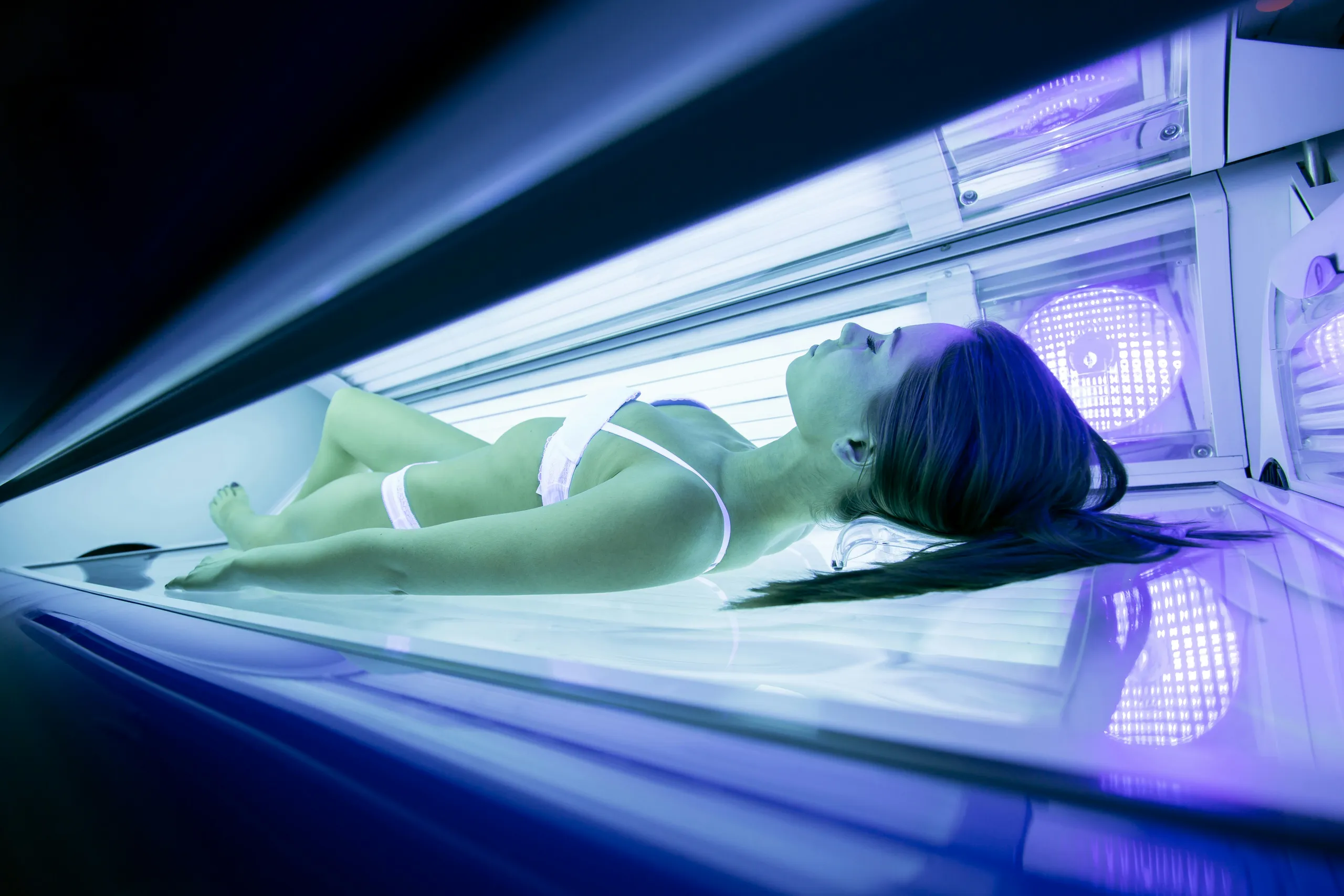 Kobieta opalająca się w solarium w niebieskim świetle lamp